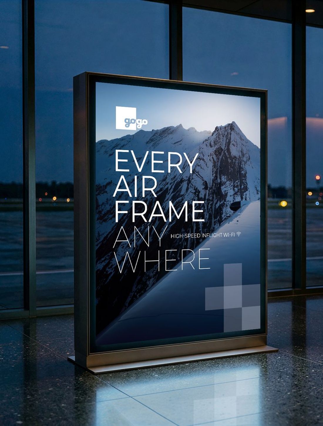 Backlit Gogo poster in a private jet terminal at dusk: a snowy mountain and the headline “Every airframe anywhere”